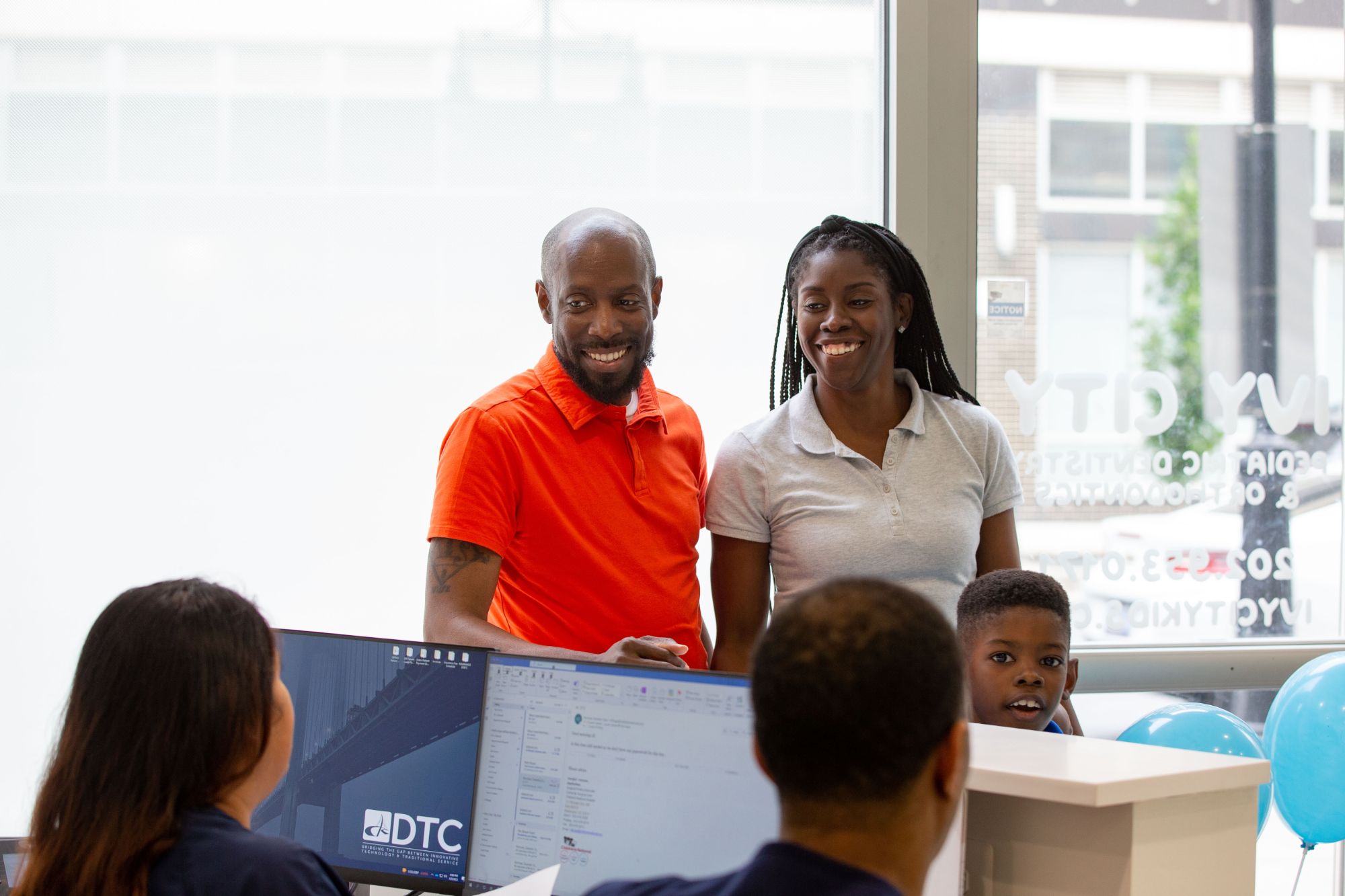Washington DC Braces - 001 Family visiting Ivy City Pediatric Dentistry & Orthodontics reception, smiling and engaging with staff, showcasing a welcoming environment for orthodontic care.